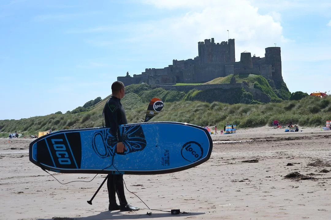 Joe holding his Loco SUP at Bamburgh, Rough Camping A Castle and Two Locos