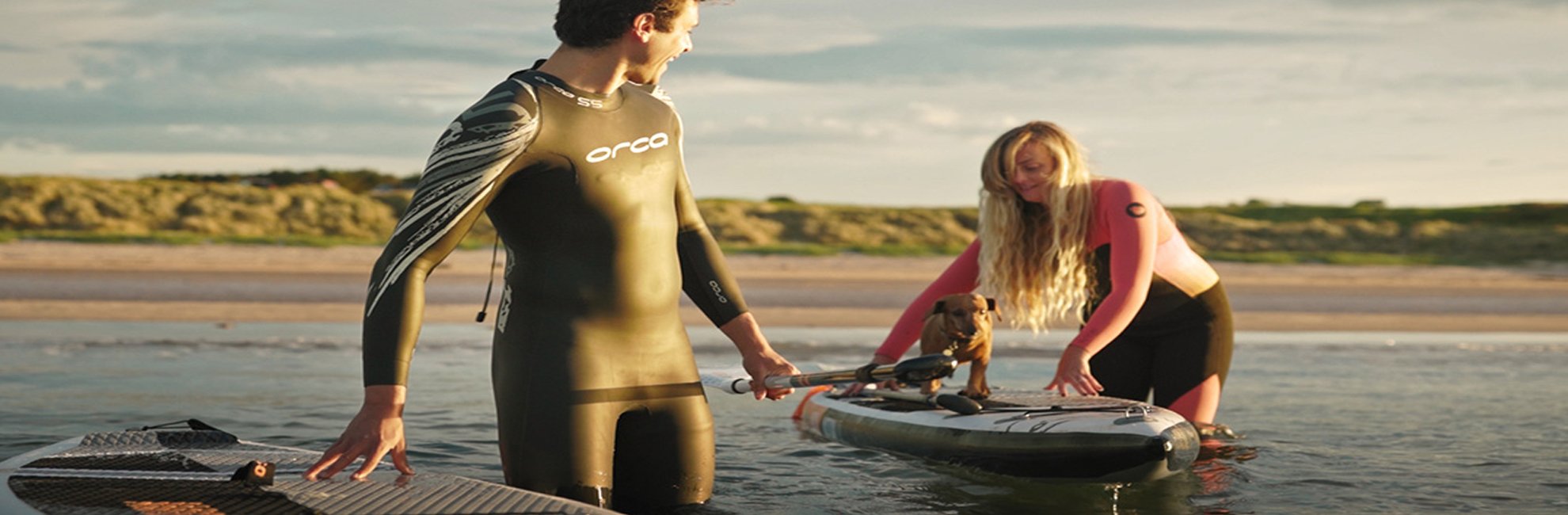 Couple with inflatable stand up paddle boards at Bamburgh