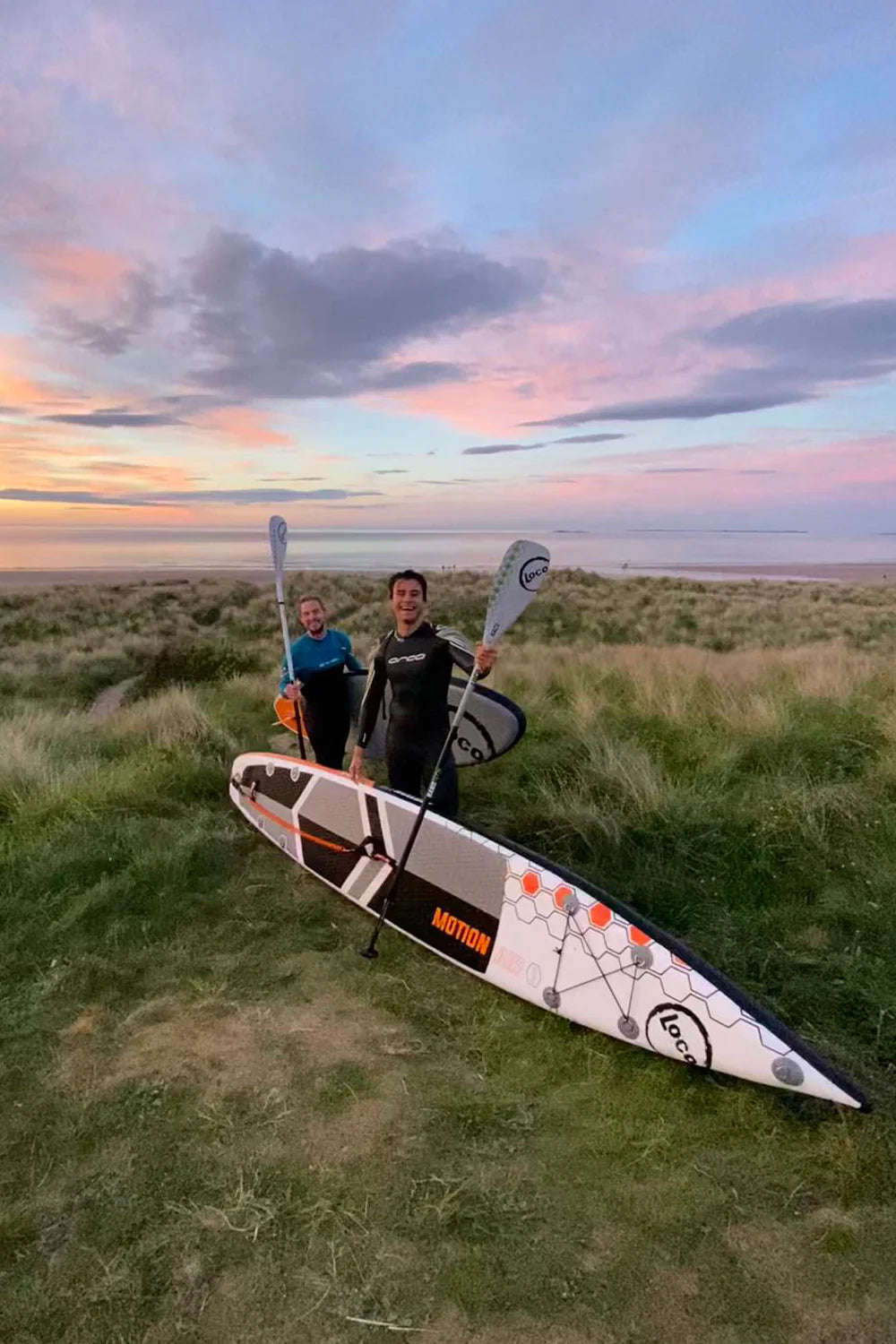 Man With Loco paddle board At Dusk Northumberland