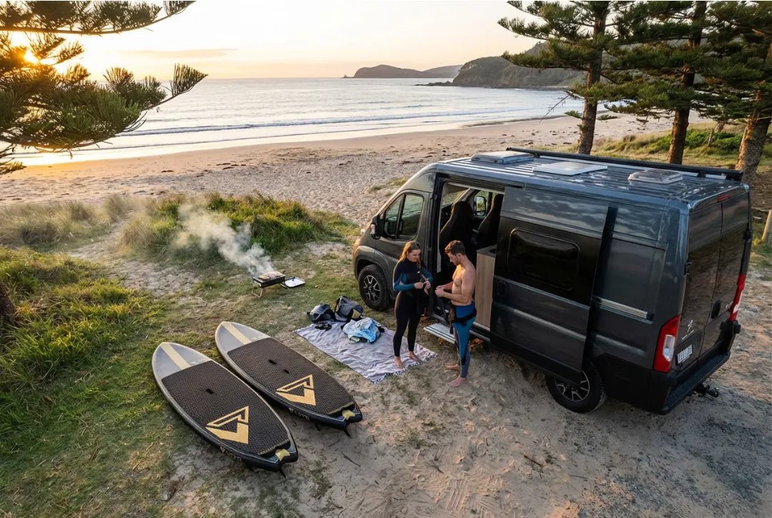 Couple with Loco inflatable SUP boards and campervan on sandy beach at tropical SUP destination at sunrise
