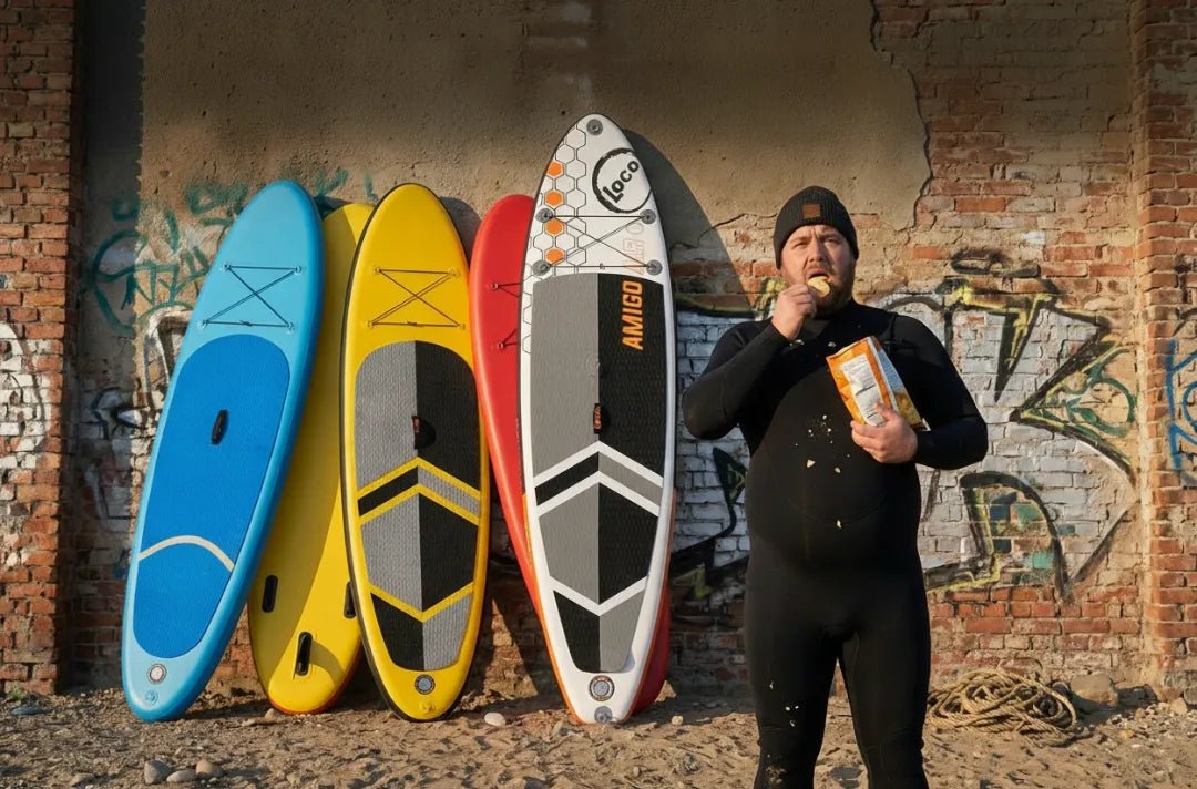 Paddleboarder comparing cheap inflatable SUP boards with premium Loco Amigo inflatable against urban graffiti wall