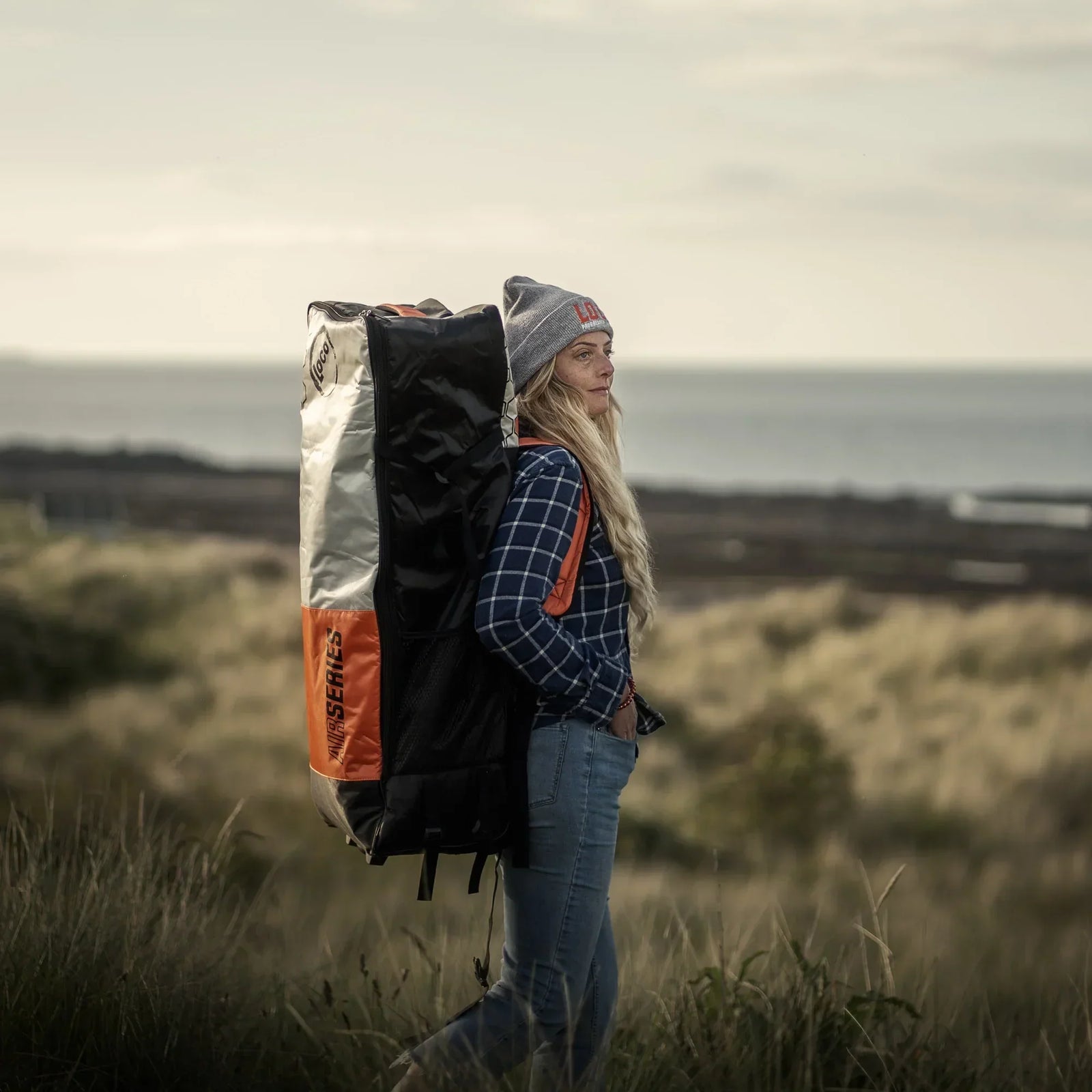 Kate carrying her stand up paddle board along the Northumberland Coast