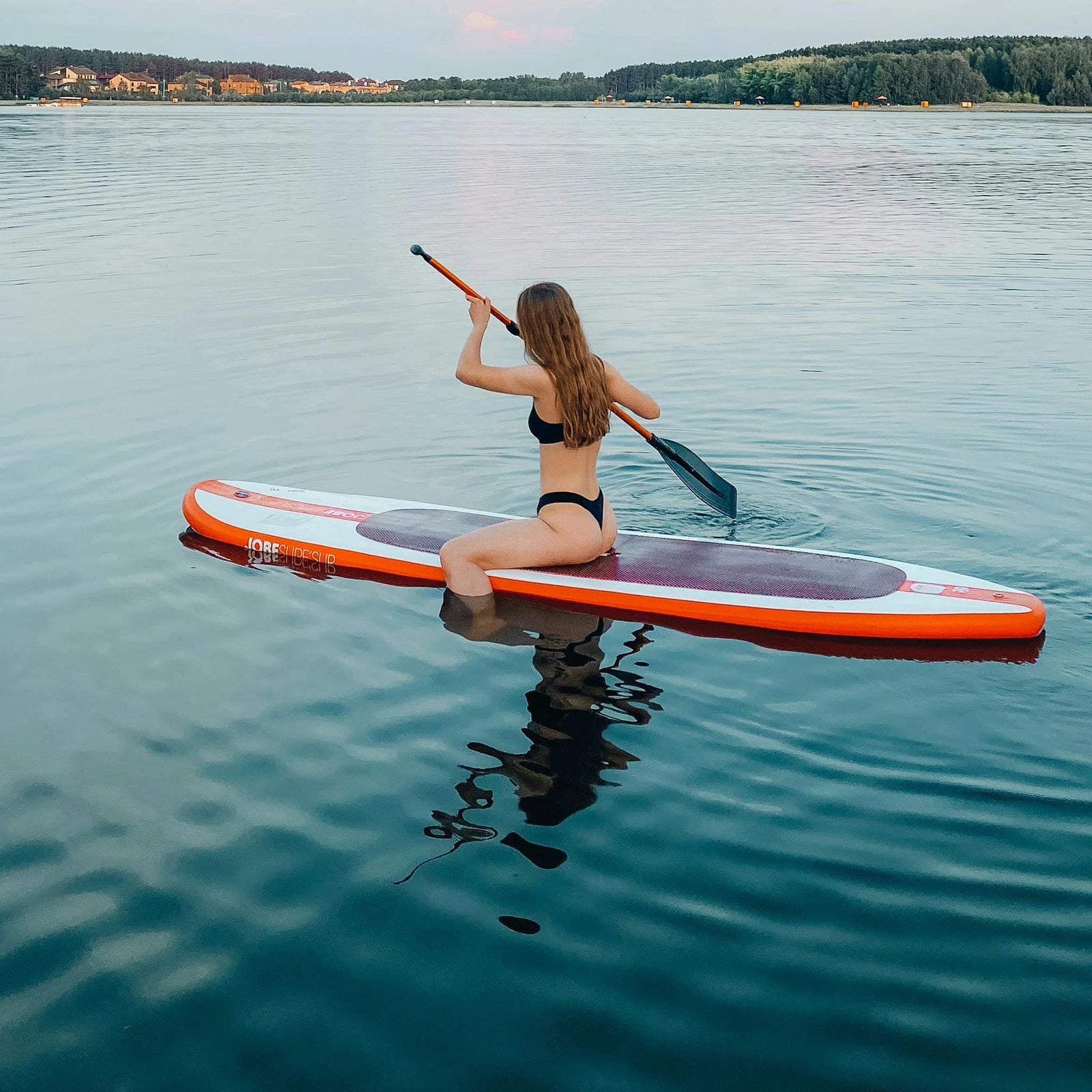 woman struggling to stand up on her generic inflatable paddle board