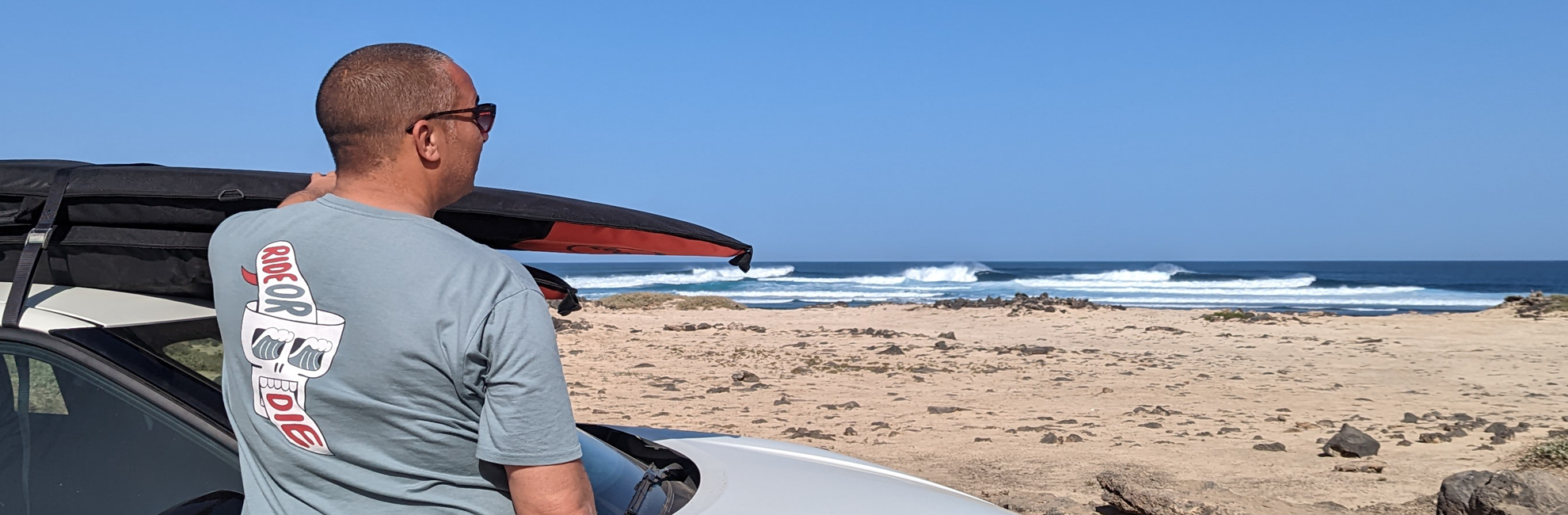 Loco Kids SUPs - guy looking out at waves in Fuerteventura with SUP on roof