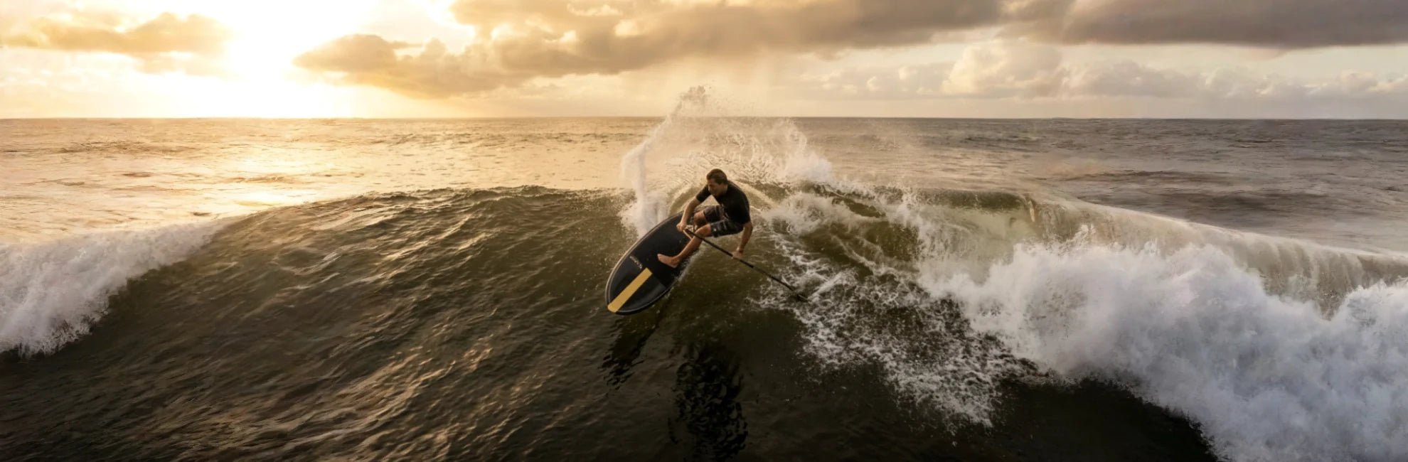 Paddle surfer smacking the lip at golden hour