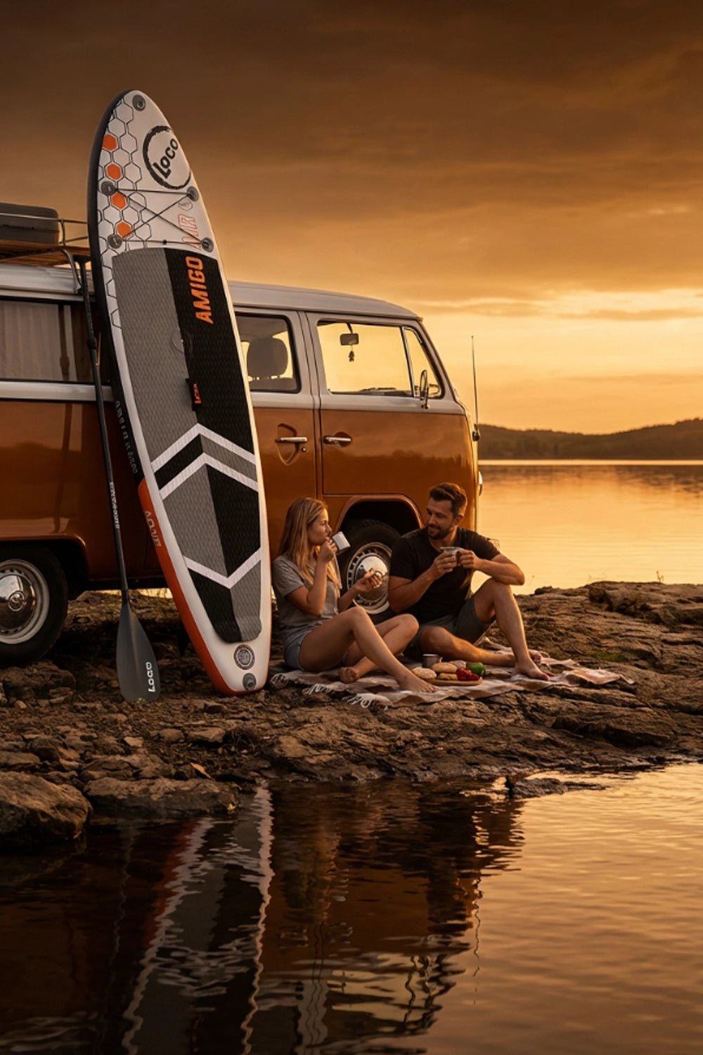 Couple having a picnic next to their camper van at sunset