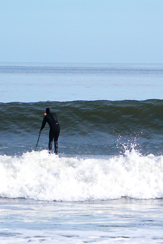 SUP Surfer heads out back 