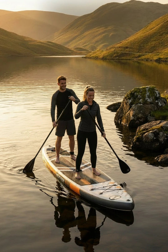 Couple paddleboarding on a tandem board at sunset