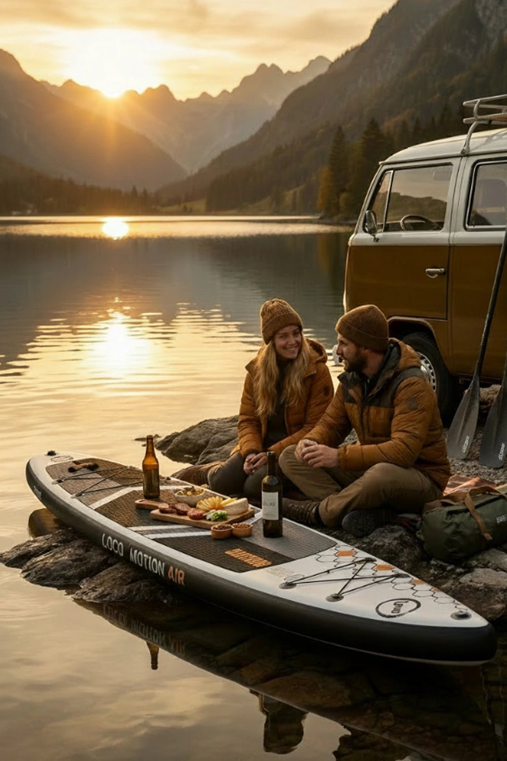 Couple having a picnic next to an alpine lake with campervan and stand up paddleboard