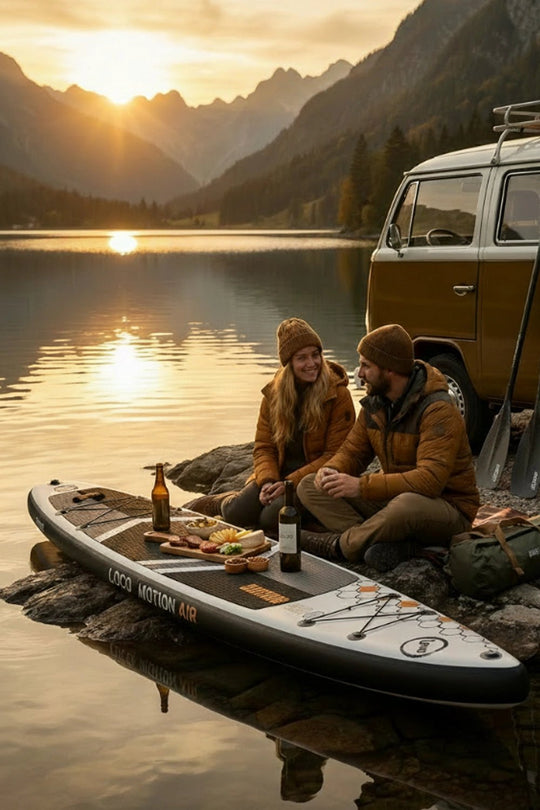 Couple having a picnic next to an alpine lake with campervan and stand up paddleboard