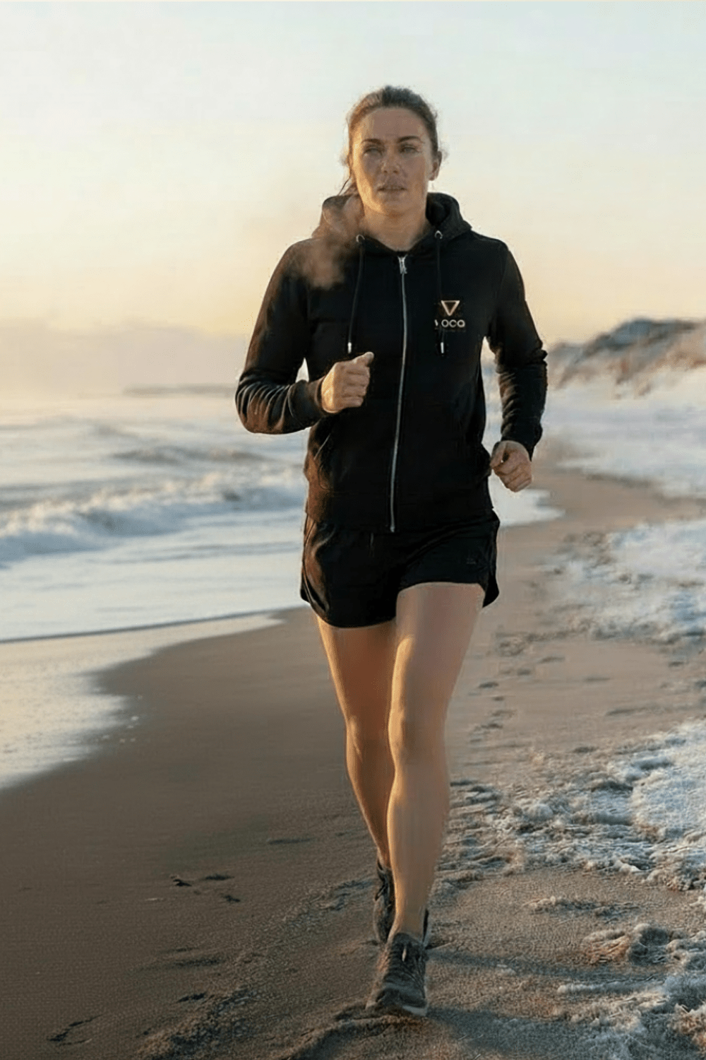 SUP girl running on beach at sunset in her toasty Loco Hoodie