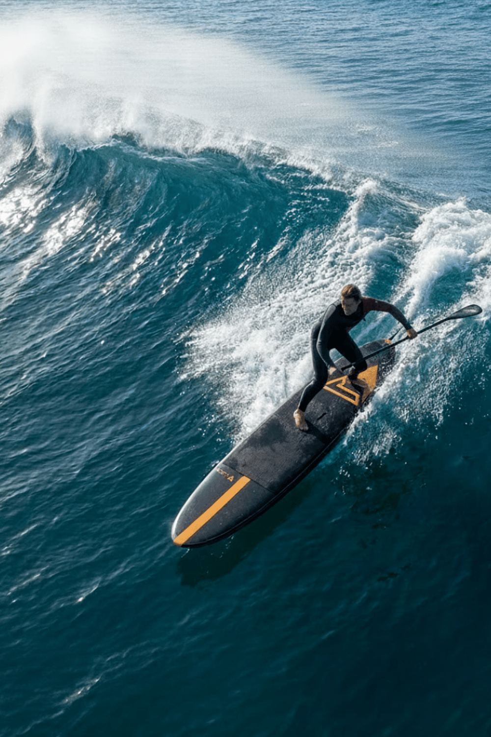 Man paddleboarding on a large wave in the ocean