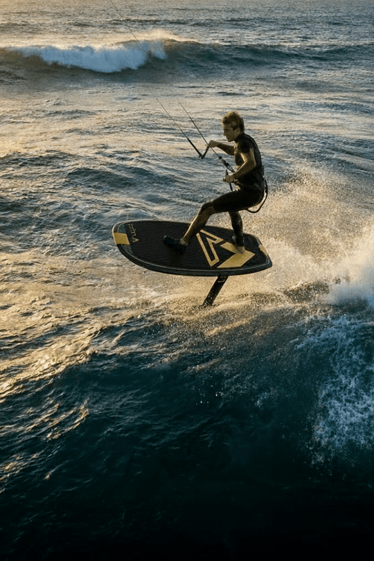 guy kite foiling on a wave at sunset