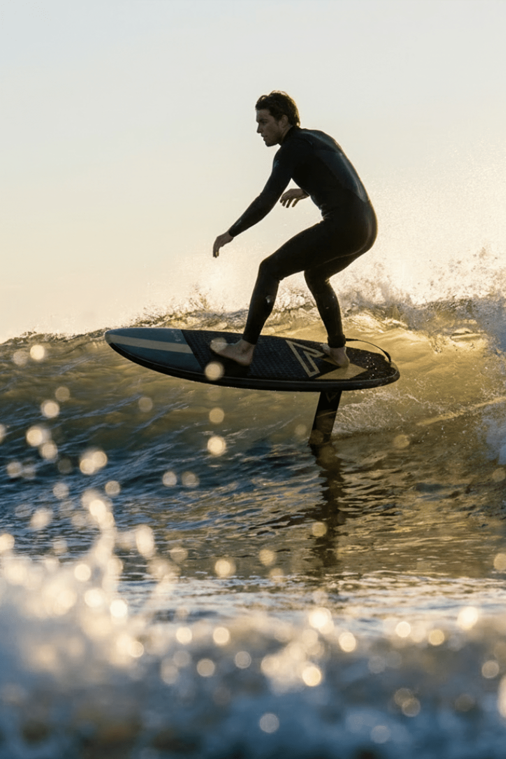 Prone foil dude arcs a smooth turn on a wave as the sun goes down
