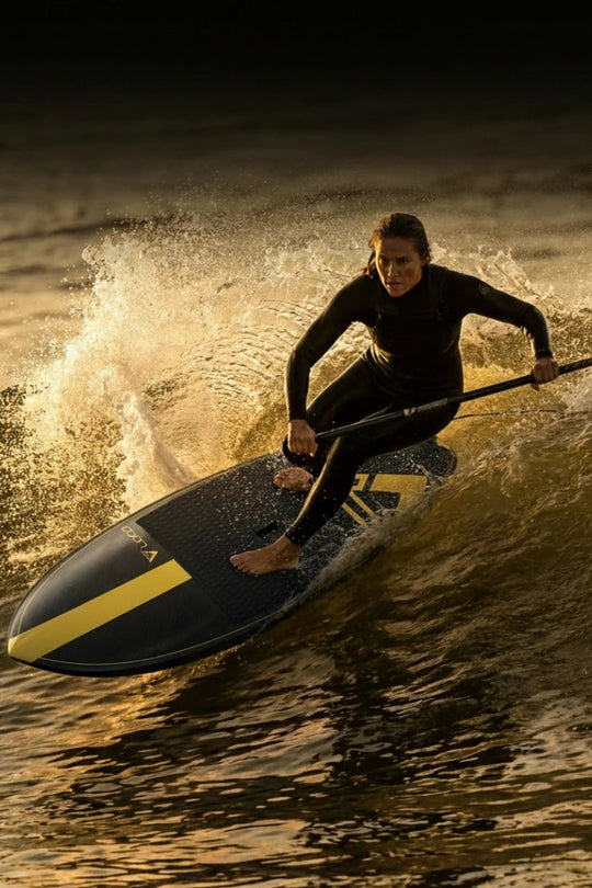 Woman paddlesurfing on a wave at sunset
